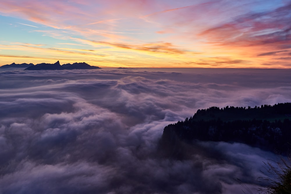 a view of a mountain with clouds below