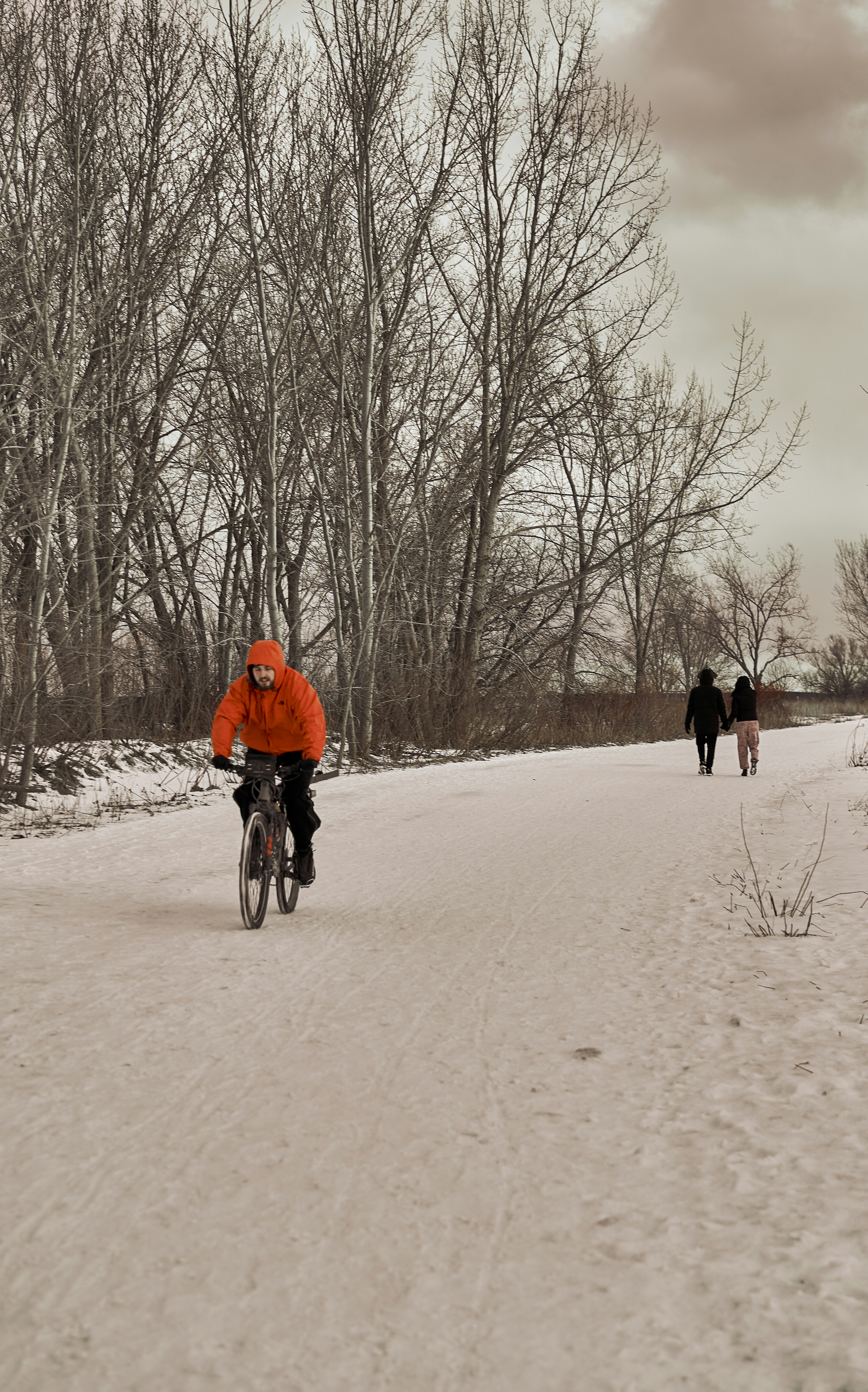 a man riding a bike down a snow covered road