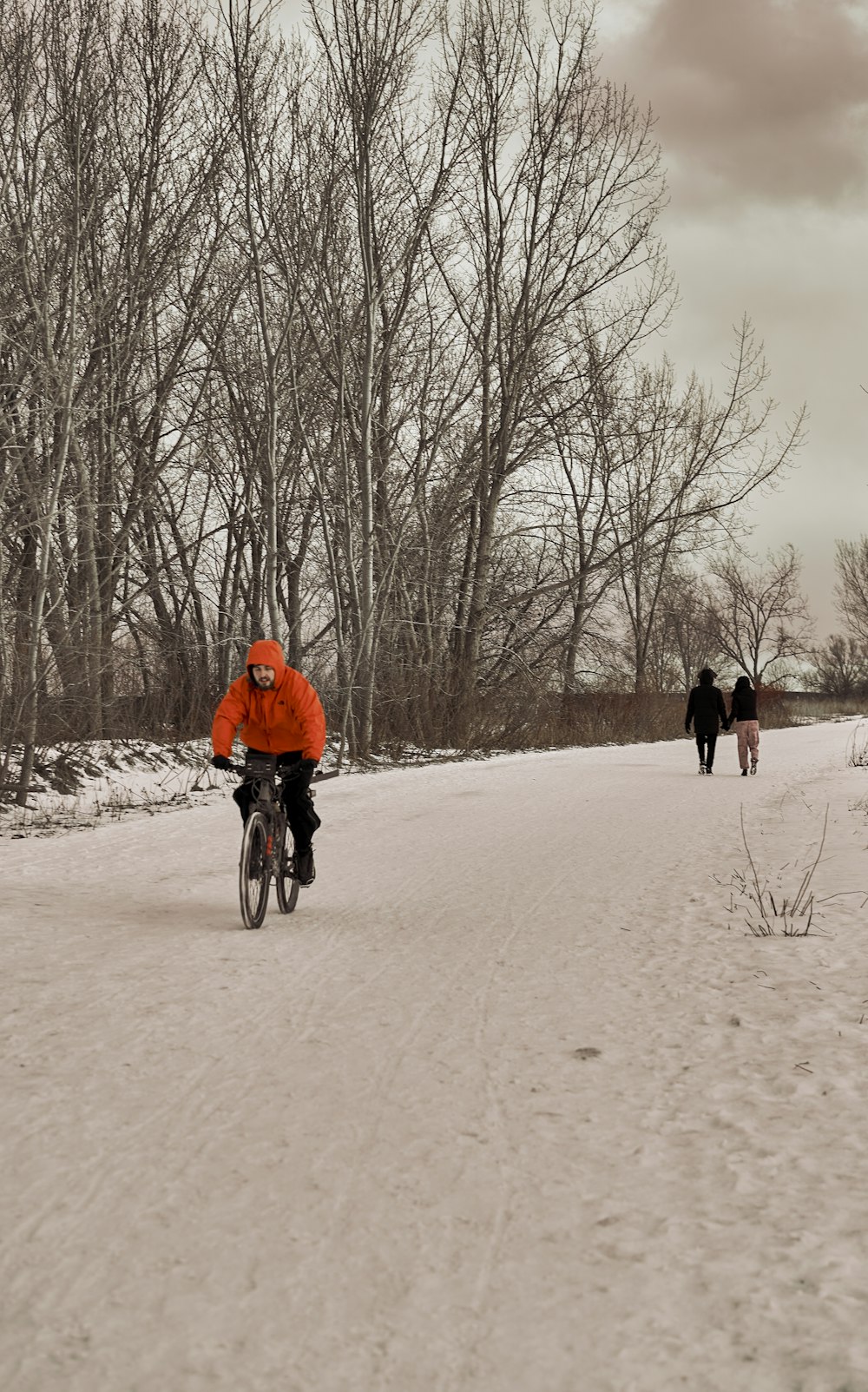 um homem andando de bicicleta por uma estrada coberta de neve