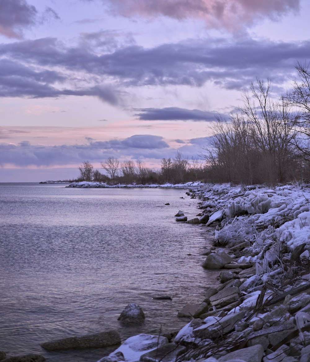 a body of water surrounded by snow covered rocks