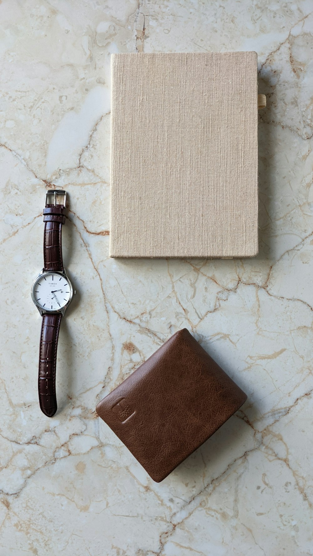 a watch, wallet, and watch sitting on a marble surface