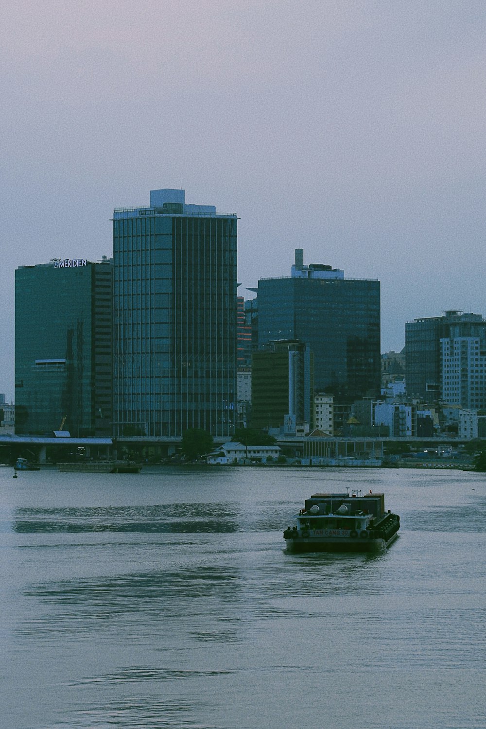 Un barco que viaja por un río junto a edificios altos