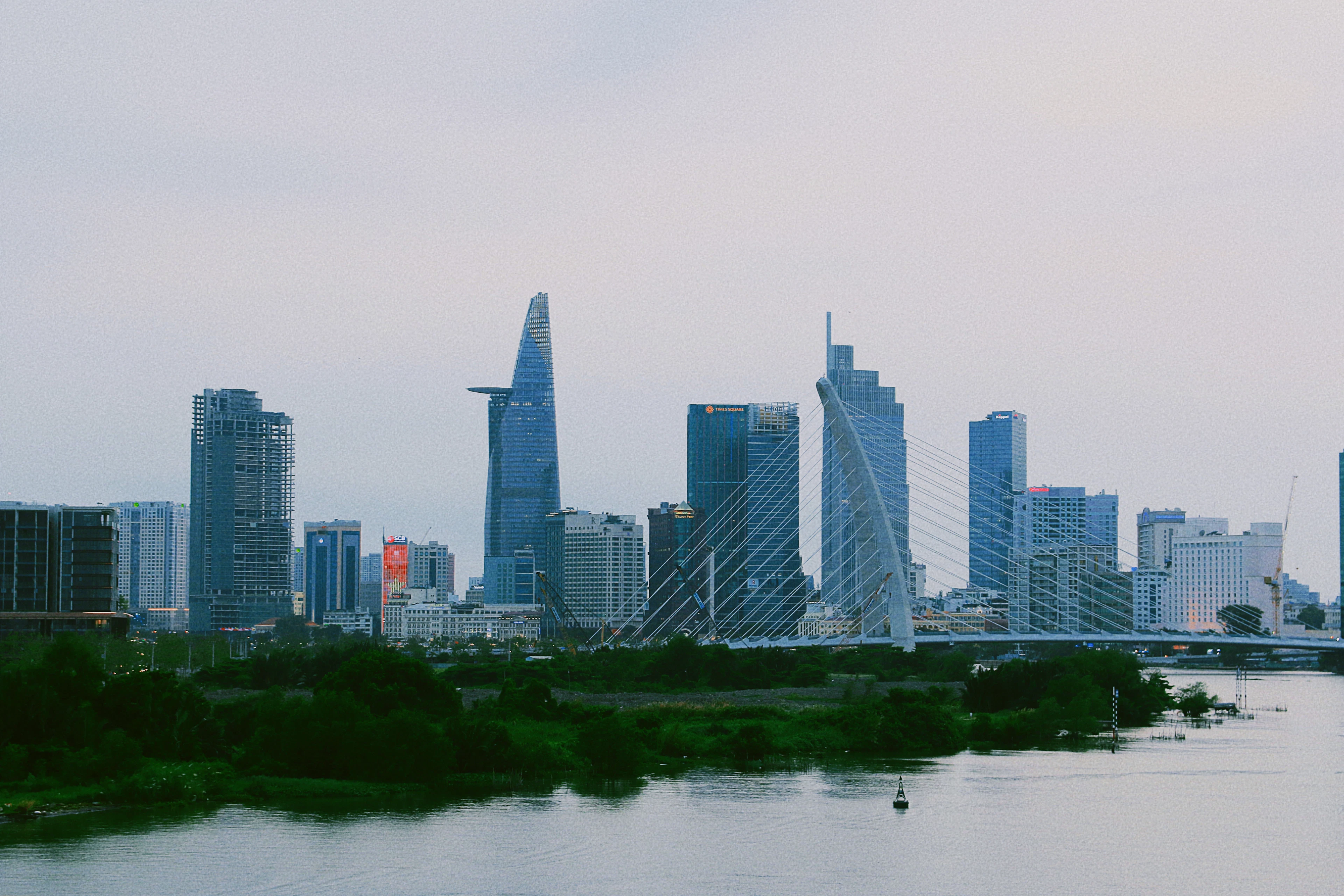 The Saigon River skyline at dusk, with the Bitexco tower and a cable-stayed bridge in view.
