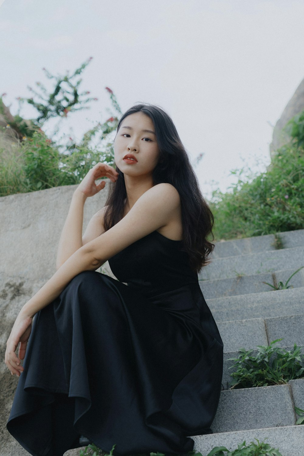 a woman in a black dress sitting on some steps