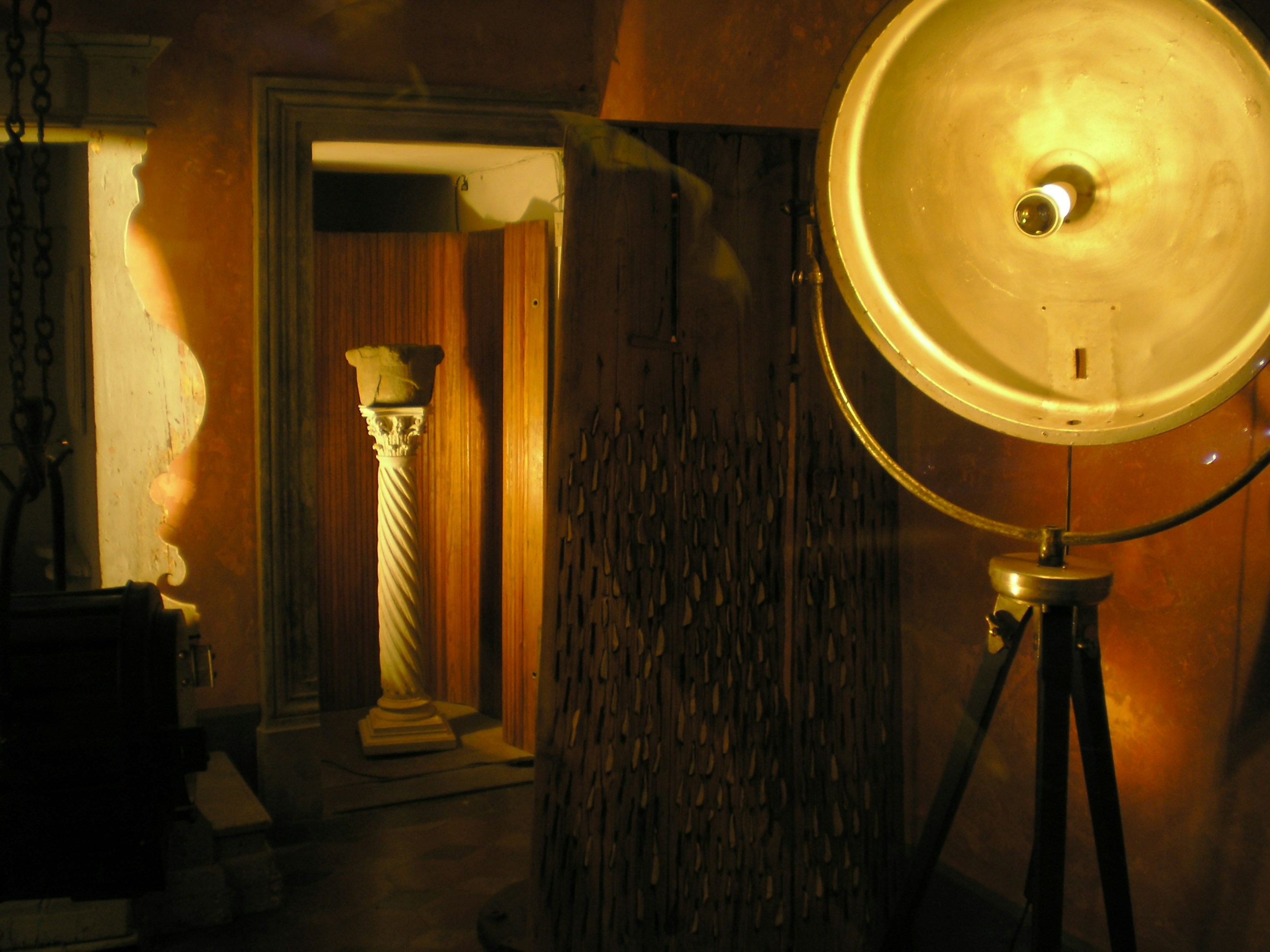 Una lámpara anticuada está en un trípode en una habitación con poca luz
