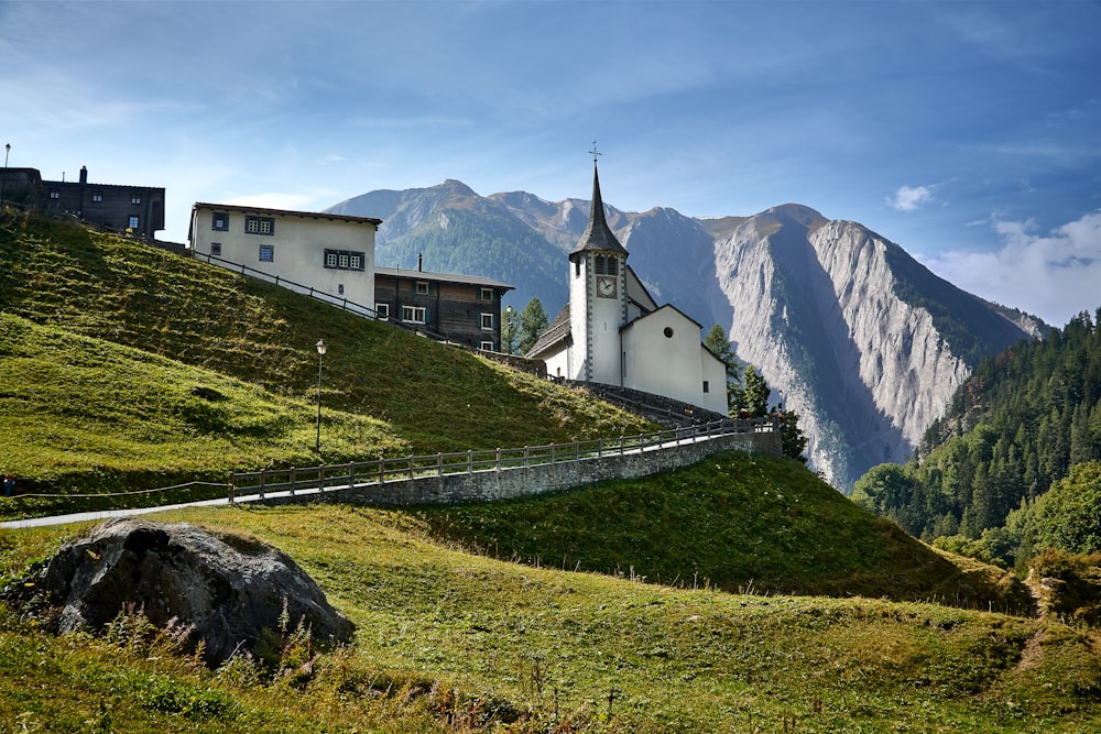 uma igreja em uma colina gramada com montanhas no fundo