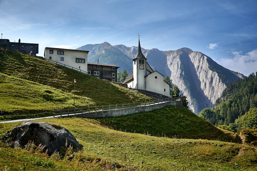 a church on a grassy hill with mountains in the background