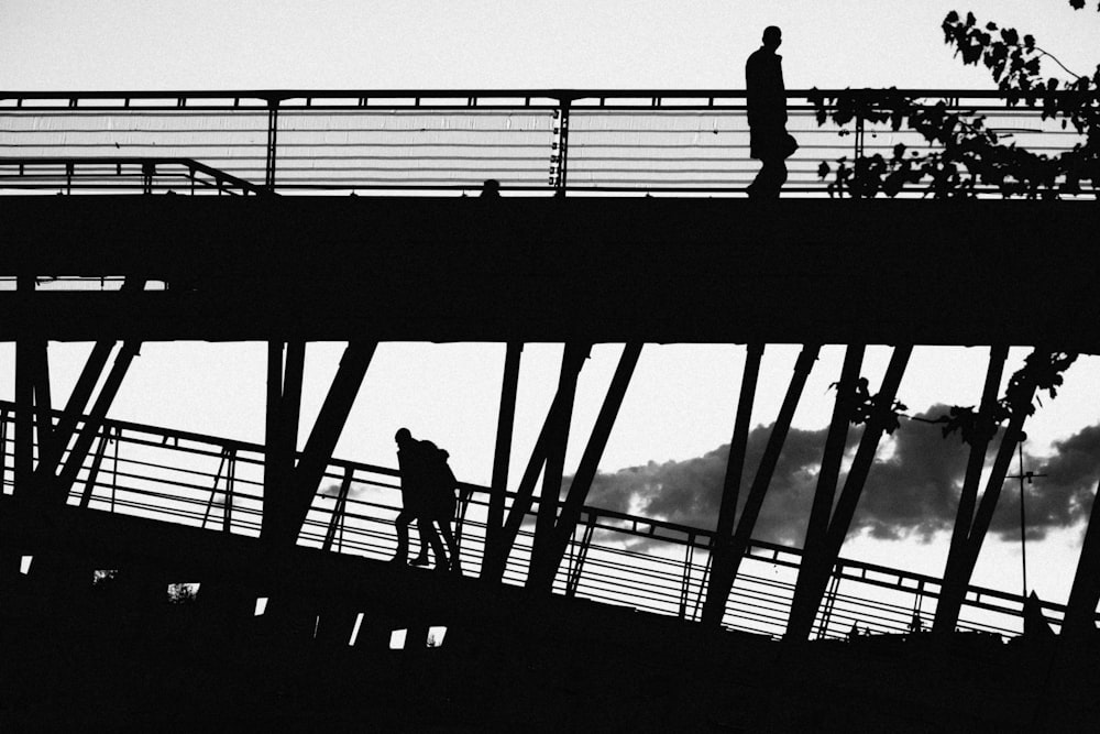 a man walking across a bridge over a river