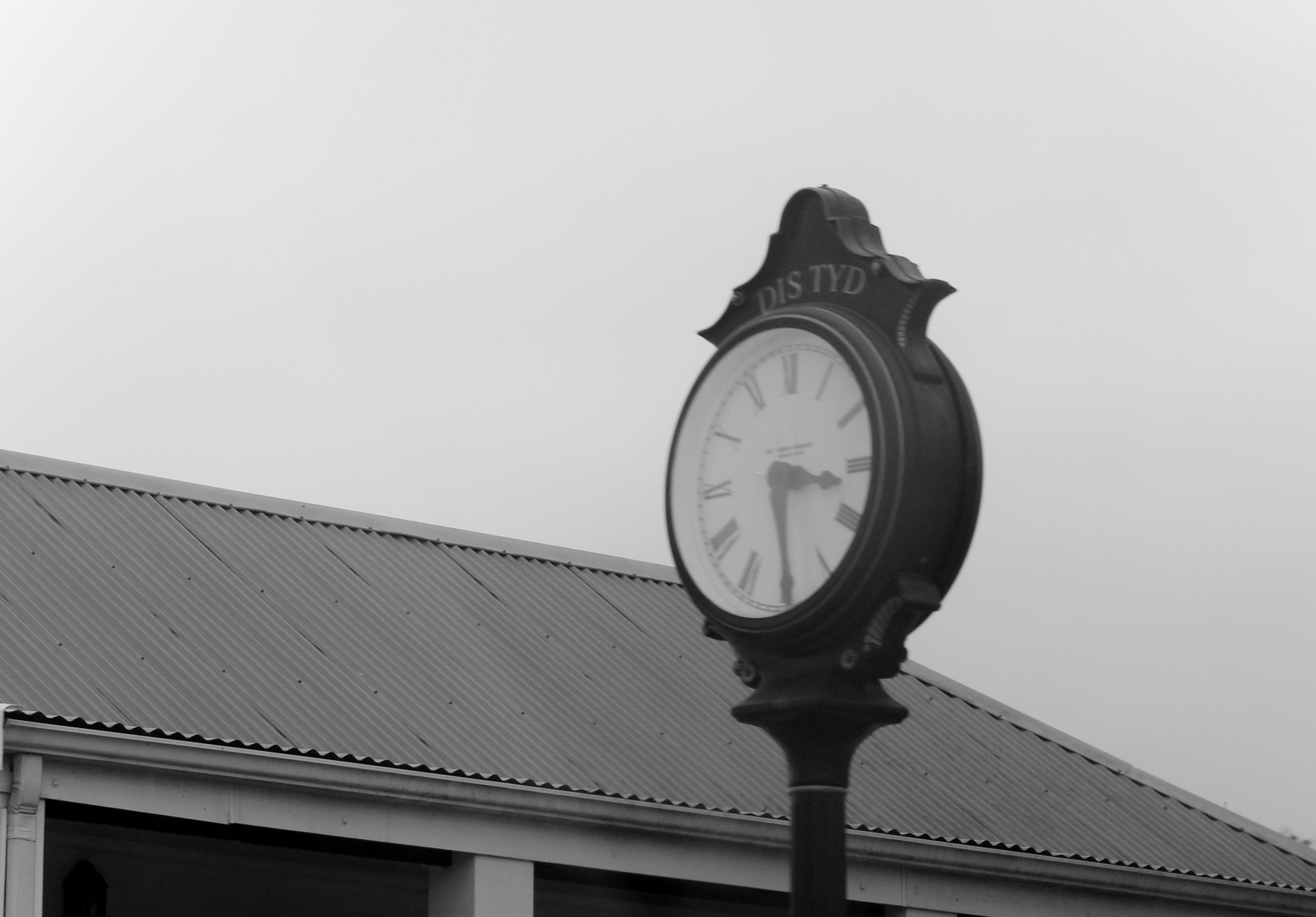 a black and white photo of a clock on a pole
