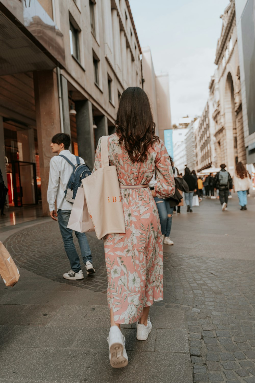 uma mulher andando por uma rua carregando sacolas de compras