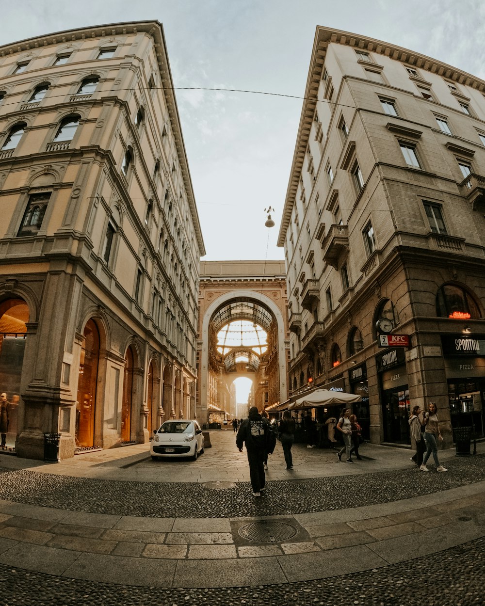 a couple of people walking down a street next to tall buildings