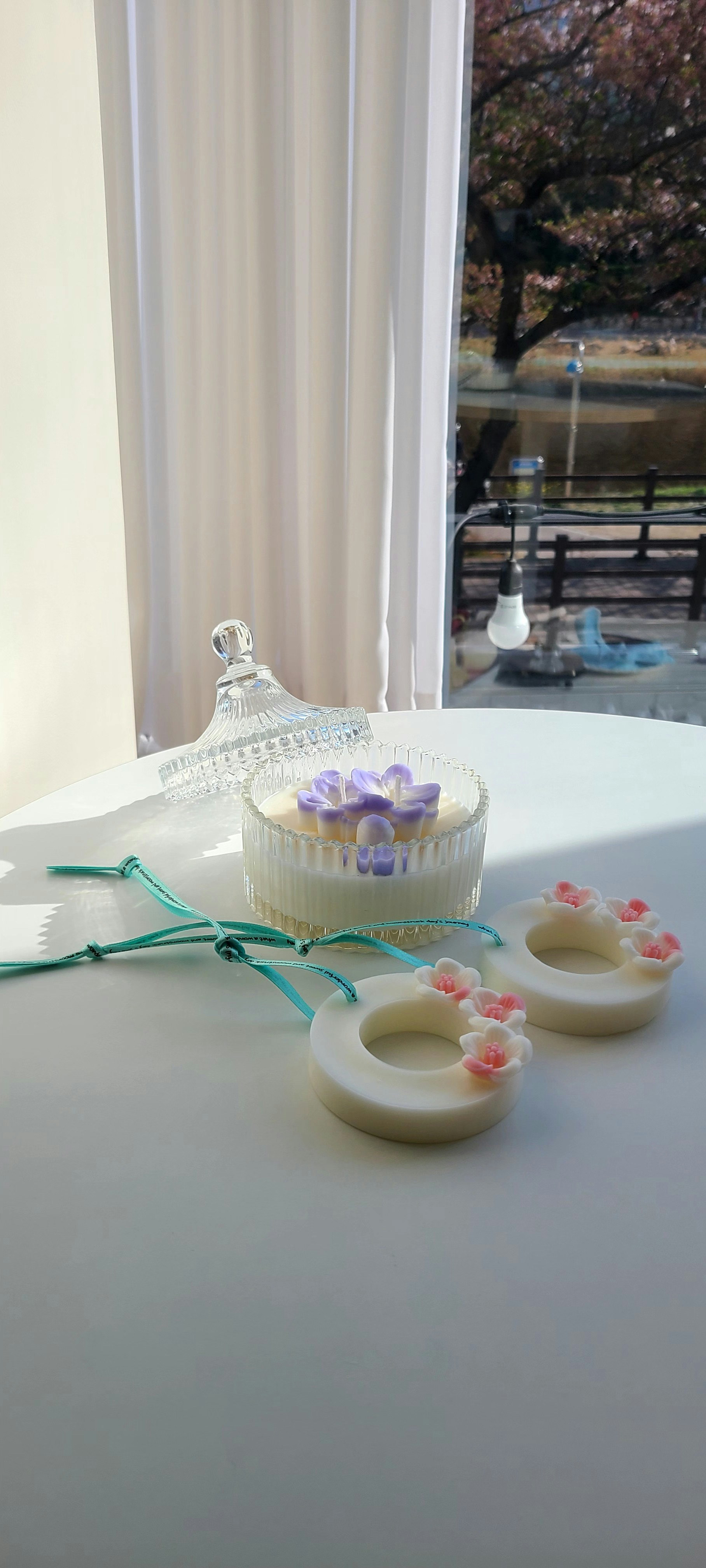 Wax melts and a floral candle sit on a white table.