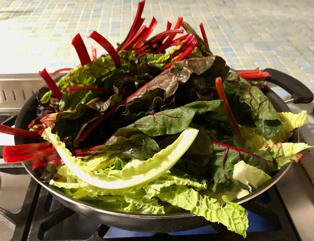 a bowl of lettuce and red peppers on a stove