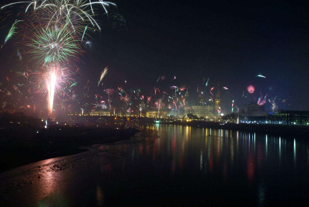 I fuochi d'artificio sono illuminati nel cielo notturno sopra l'acqua