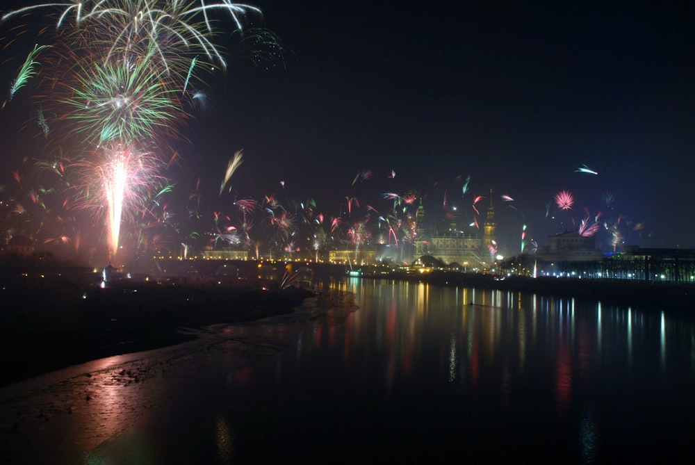 fogos de artifício são iluminados no céu noturno sobre a água