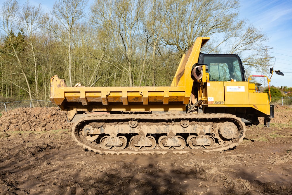a yellow bulldozer sitting on top of a dirt field