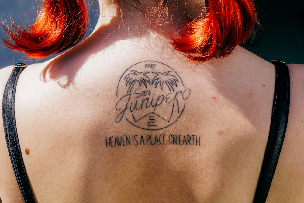 a woman with red hair has a tattoo on her back