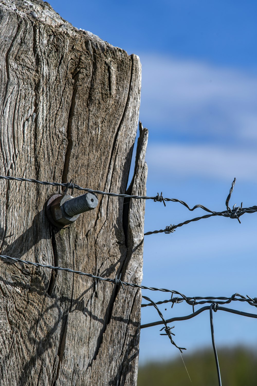 a close up of a wooden post with barbed wire