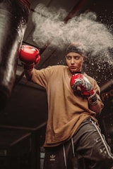 a young man wearing red boxing gloves and a brown t - shirt