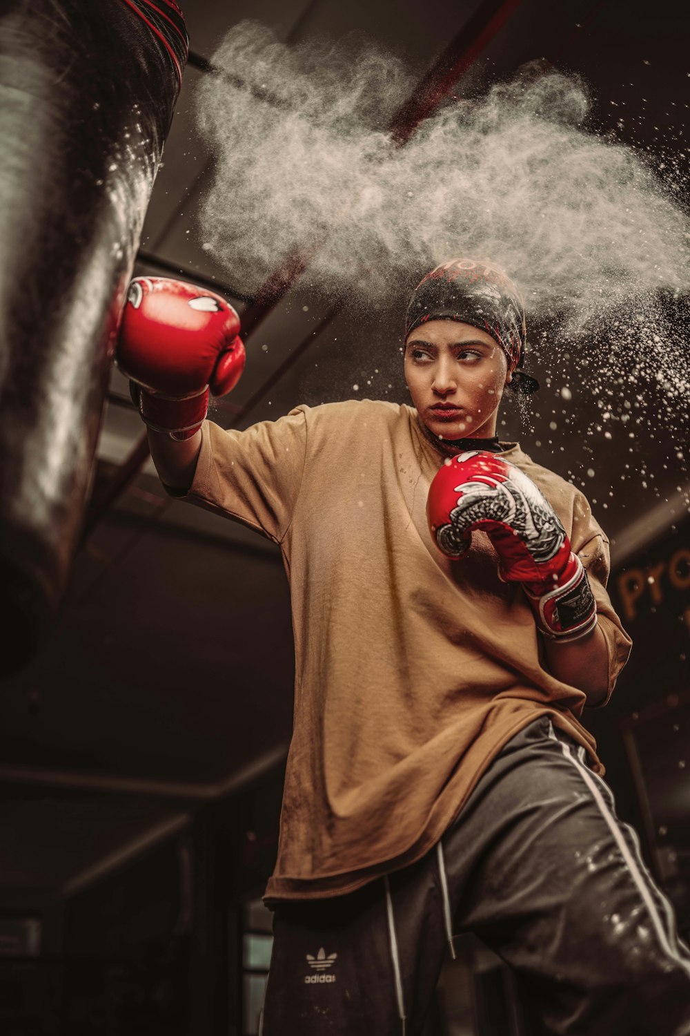 a young man wearing red boxing gloves and a brown t - shirt