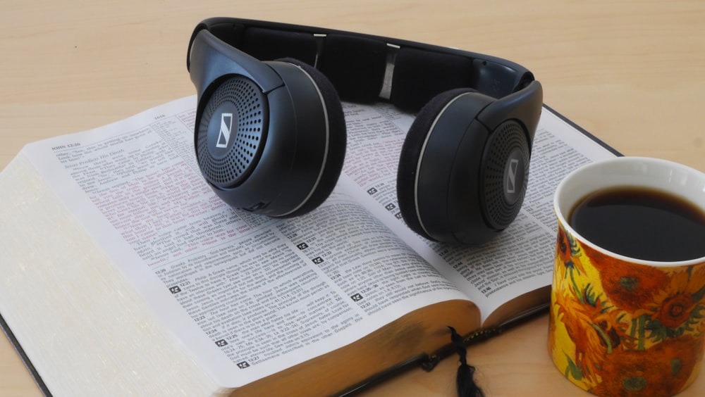 a book with headphones on top of it next to a cup of coffee