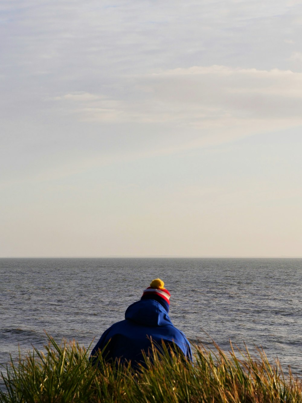 Eine Person, die an einem Strand sitzt und auf den Ozean blickt