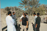 Group of cooperative members discussing plans outdoors near palm trees.