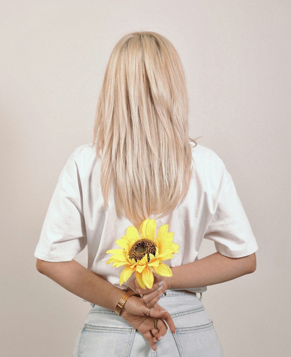 a woman with blonde hair holding a sunflower