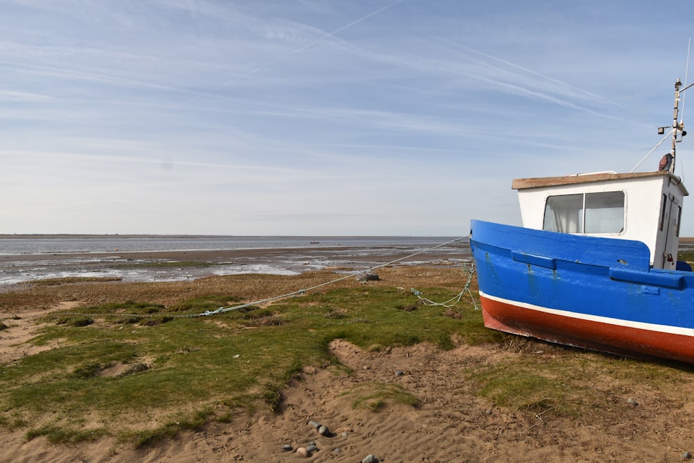 a blue and white boat sitting on top of a sandy beach