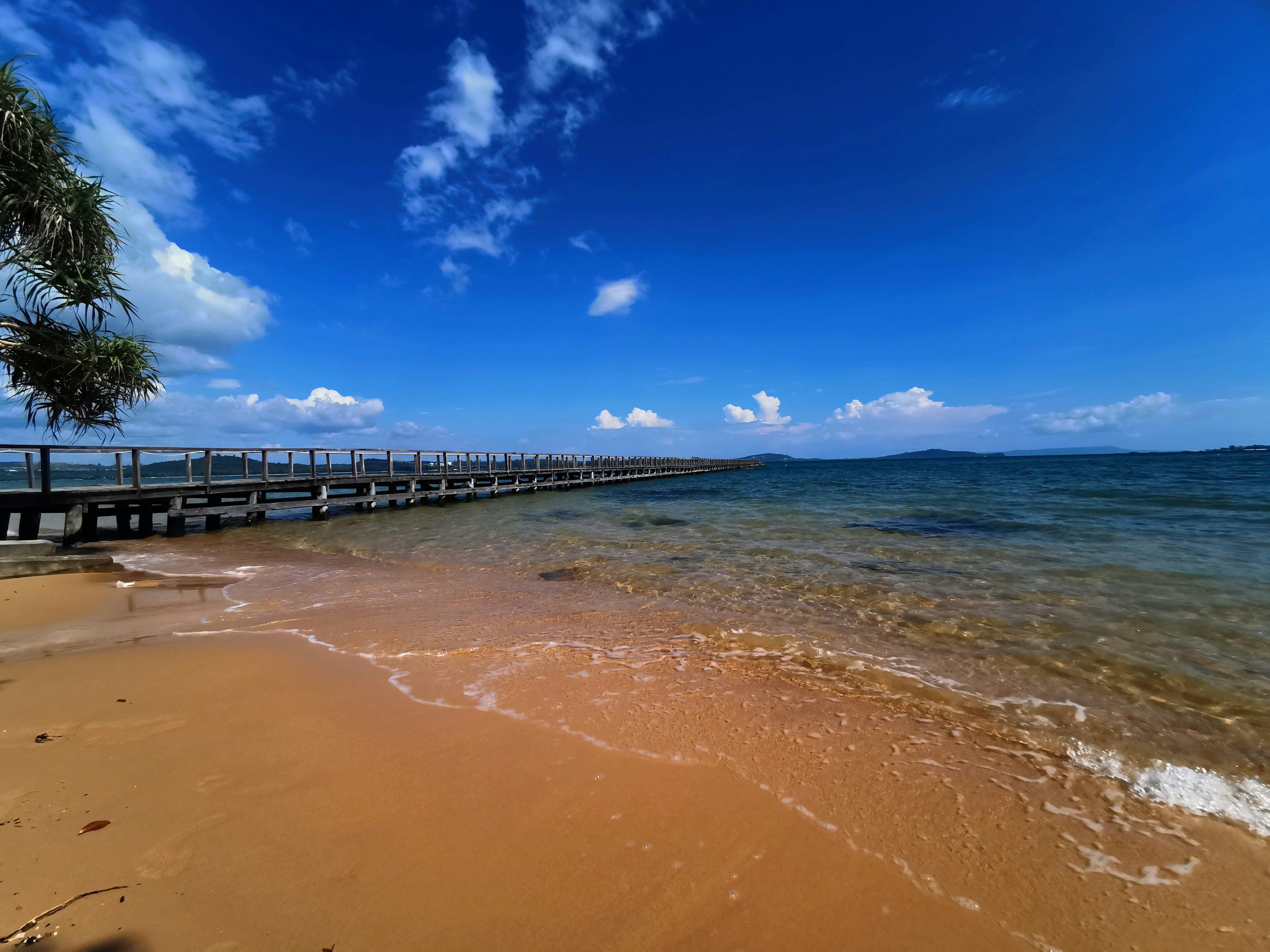 A beach with a pier and a body of water photo – Free Blue Image on Unsplash