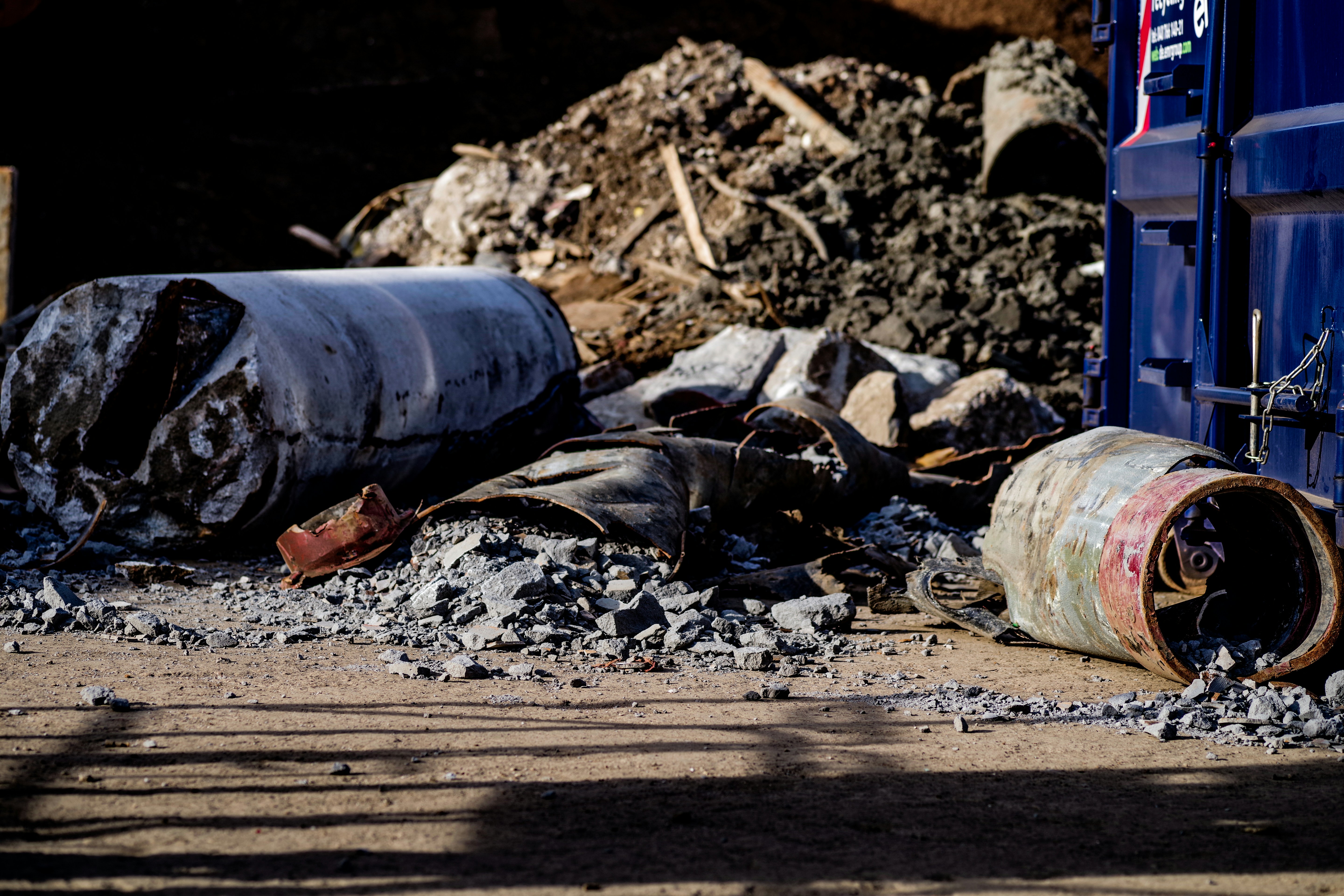 a pile of rubble next to a blue dumpster