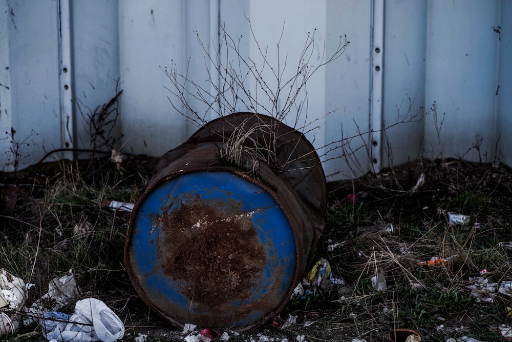 a trash can sitting in the grass next to a fence