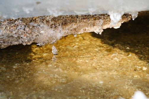 A close-up of melting ice cubes dripping water on a wooden surface.
