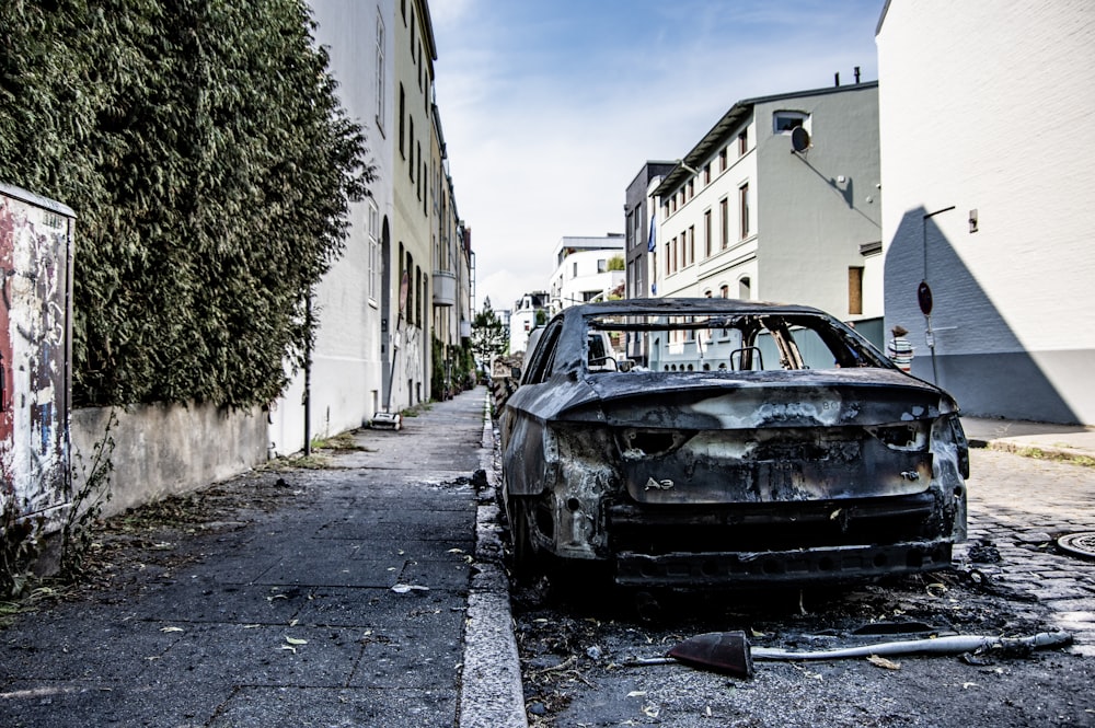 a burnt out car parked on the side of a road