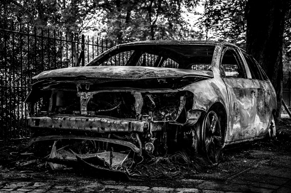 a burned out car sitting in the middle of a yard