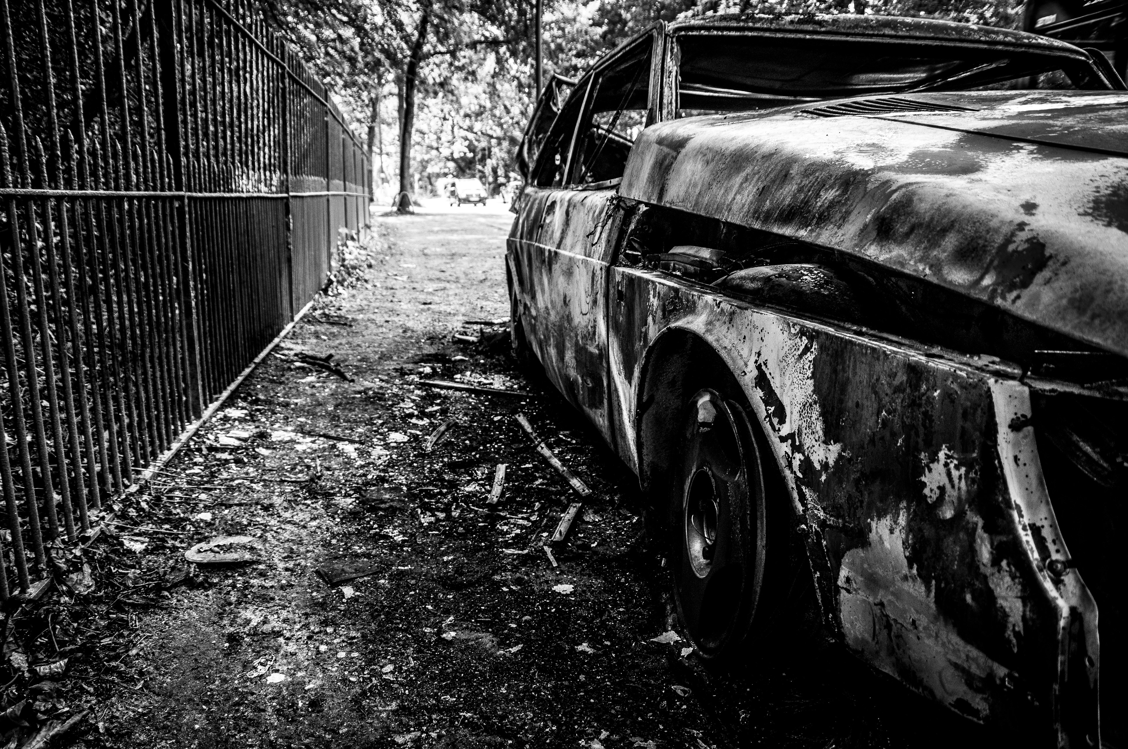 an old rusty car parked in front of a fence