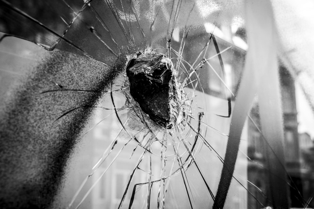 a broken glass window with a building in the background