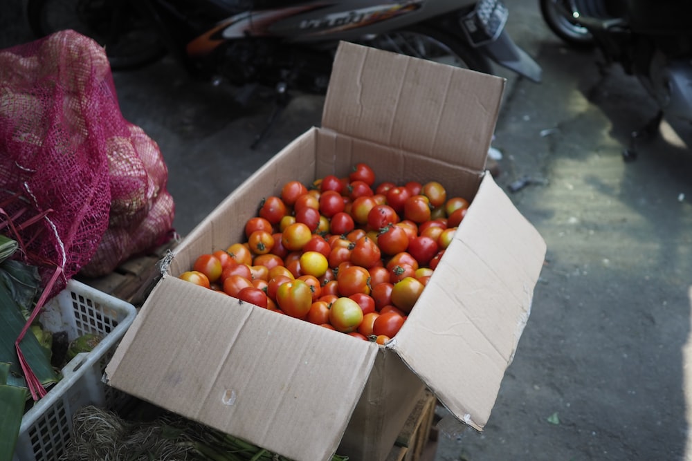 a cardboard box filled with lots of red and yellow apples