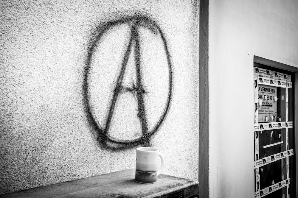 a black and white photo of a coffee mug on a shelf