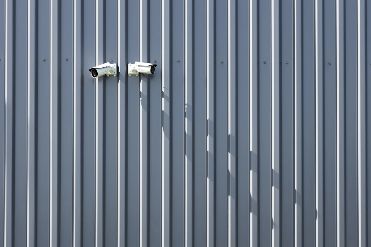 Two security cameras mounted on an exterior metal wall