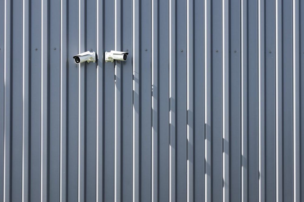 two security cameras on a metal wall