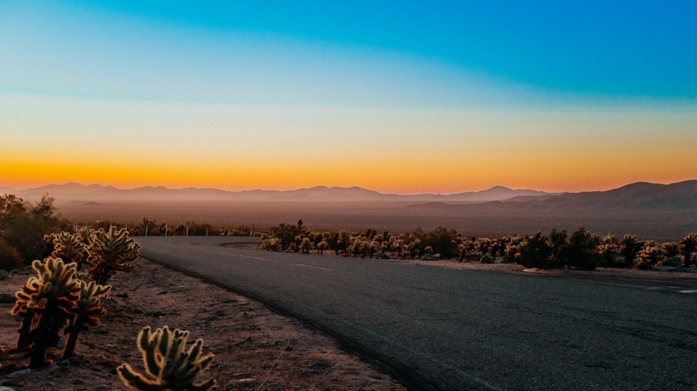 a road in the middle of a desert with mountains in the background