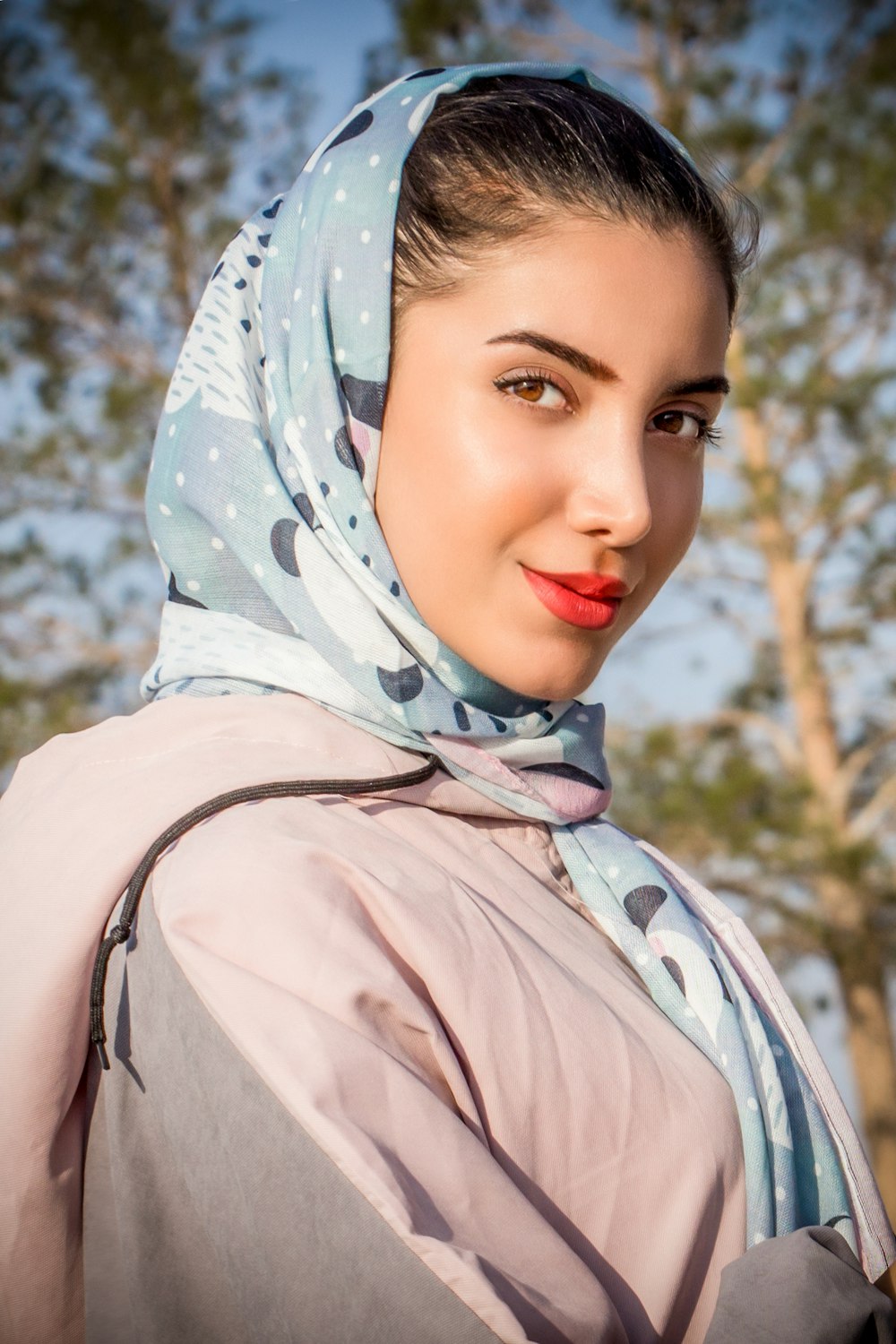 a woman wearing a headscarf with trees in the background