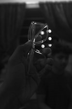 Close-up of hands holding eyeglasses with a blurred clinic background.