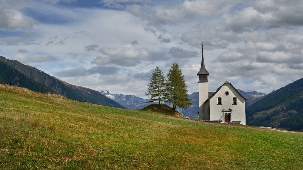 a small church on a hill with mountains in the background