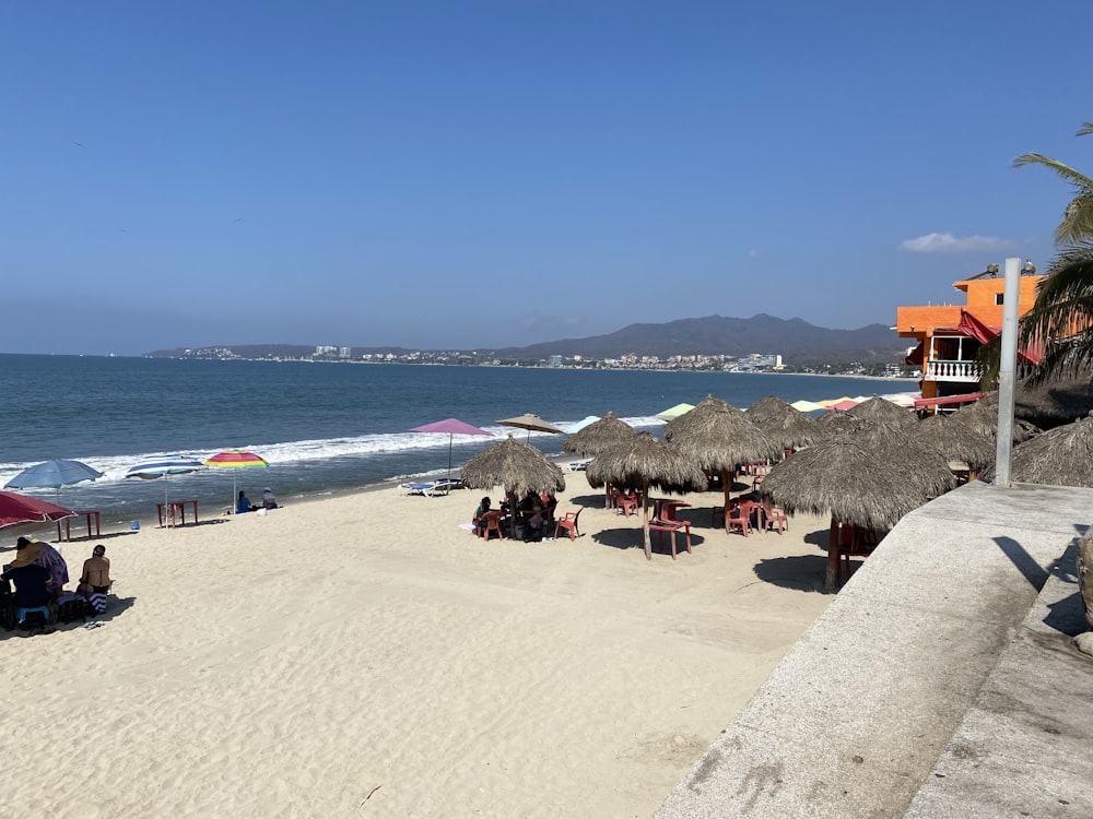 una playa de arena con sombrillas y gente sentada en ella