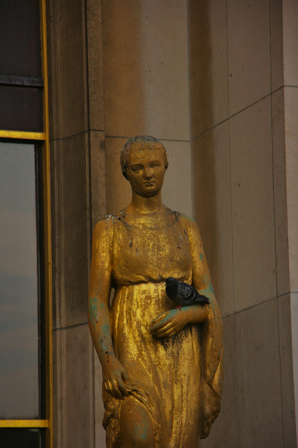 a gold statue of a woman holding a black cat