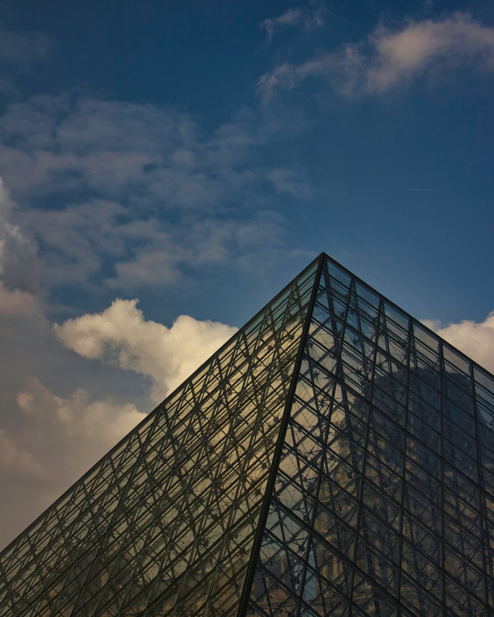 a very tall glass pyramid with a sky background