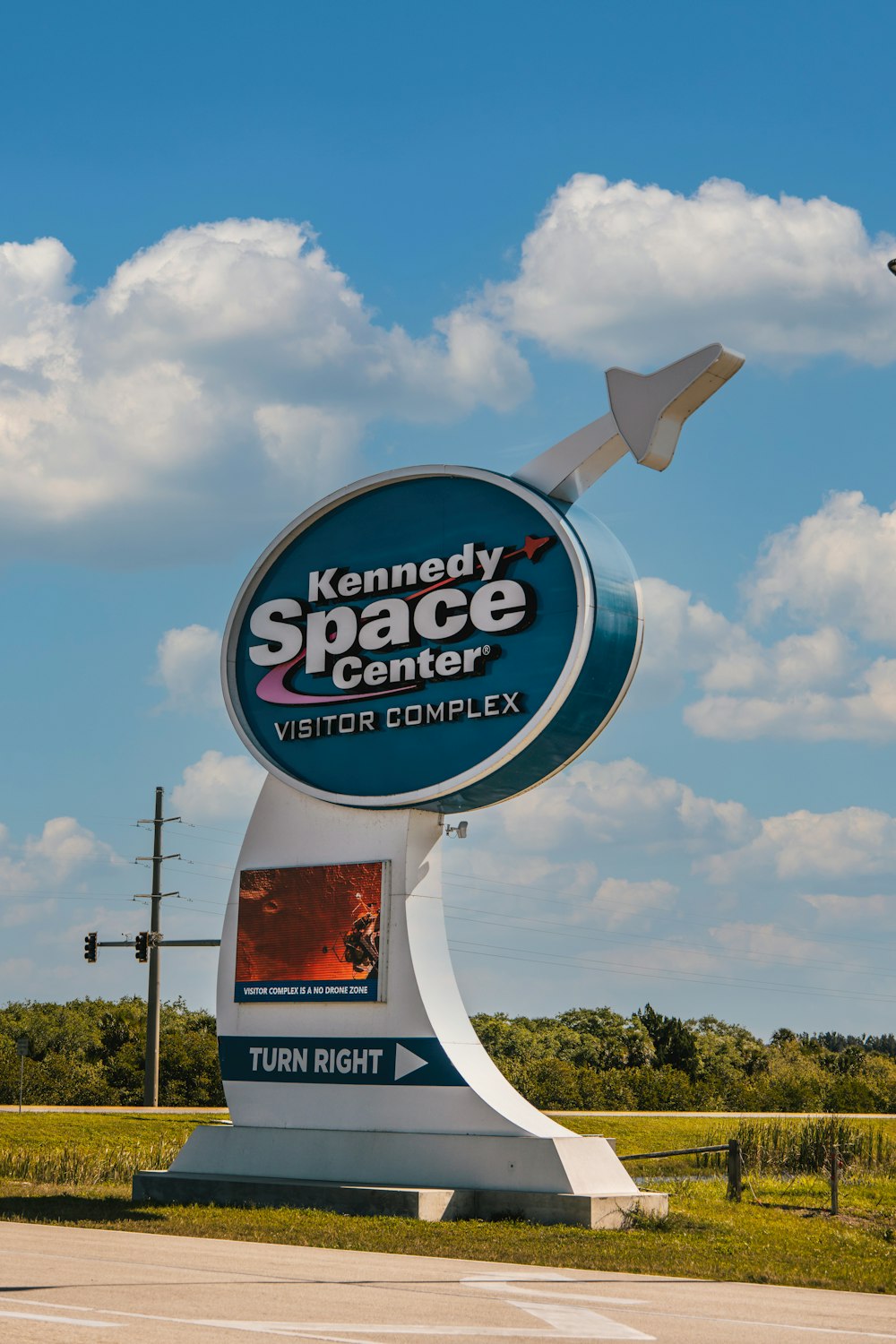 a sign for a space center with a plane flying over it