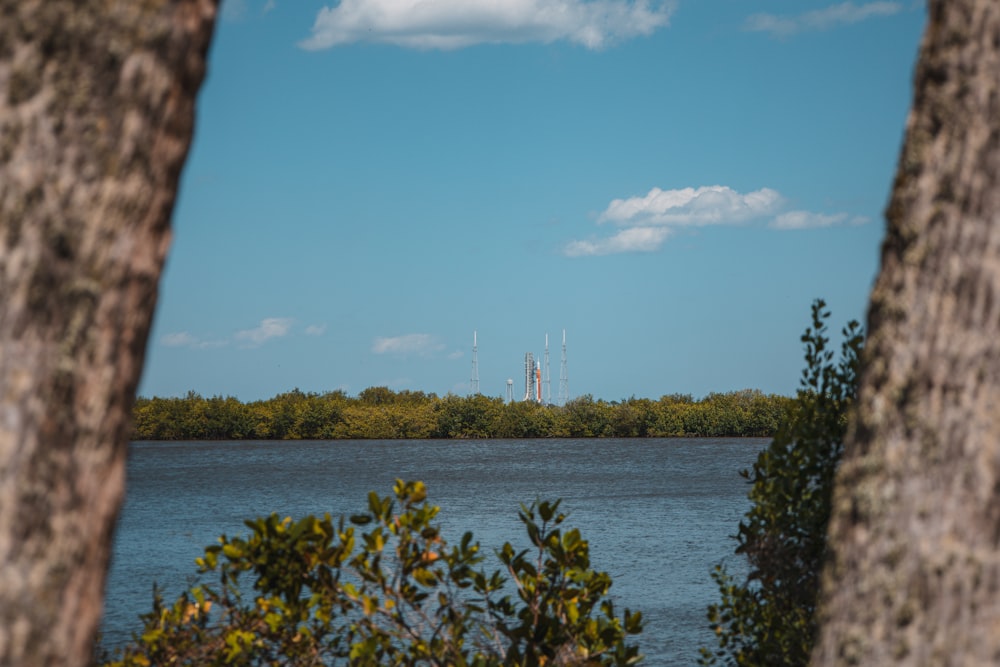 a body of water surrounded by trees and a blue sky